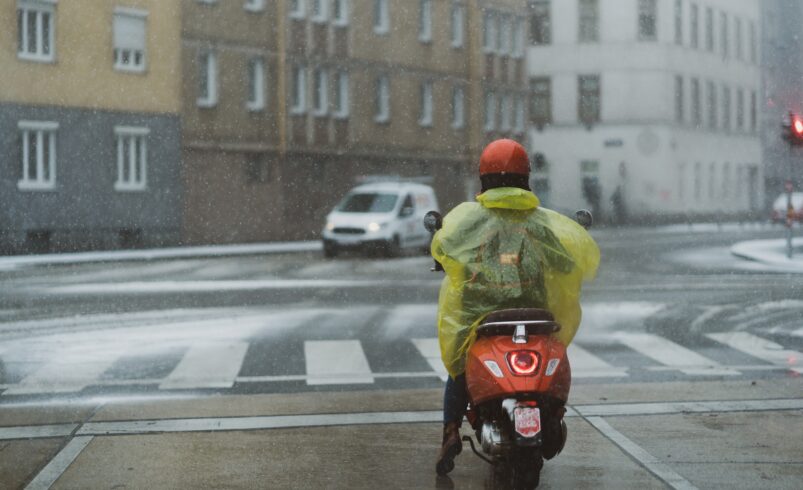 Motorcyclist with raincoat on snowy road