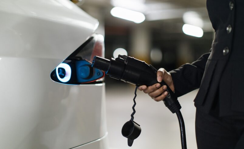 Owner carrying power supply cable to e-car port in basemant