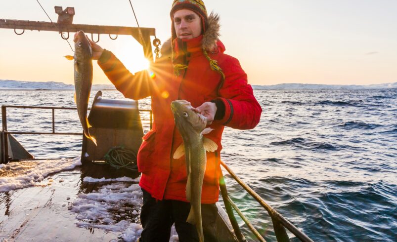 Young fisherman on the boat with two large fish