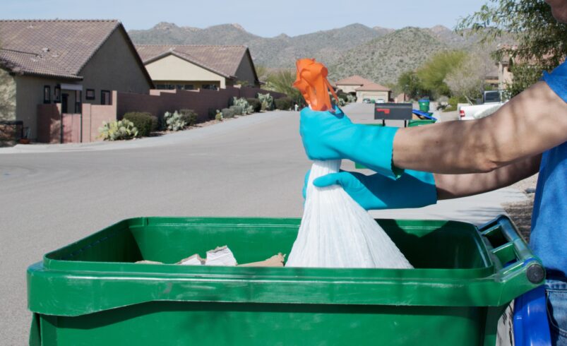 Man putting the garbage into the bin for garbage collection day.