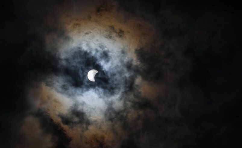 Solar eclipse with the moon shining through dark clouds in Waco, Texas