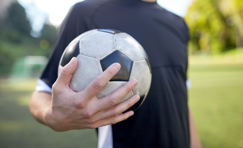 close up of soccer player with football on field