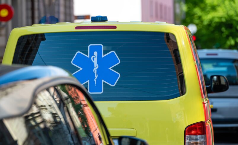 a yellow ambulance emergency car parked on the side of a crowded street, close up, selective focus